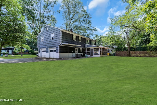 back of house with a lawn, a sunroom, aphalt driveway, an attached garage, and fence