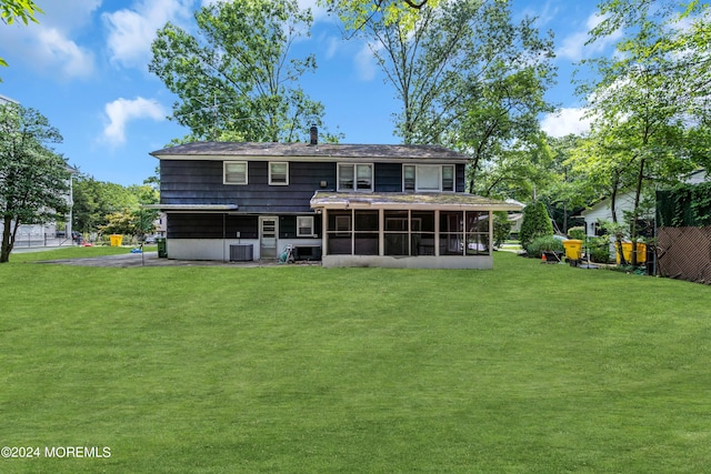 rear view of house featuring a lawn, a sunroom, and central air condition unit