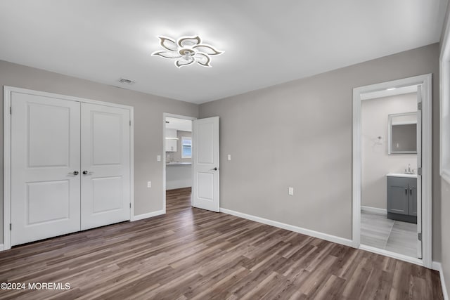 unfurnished bedroom with light hardwood / wood-style floors, sink, ensuite bath, and a closet