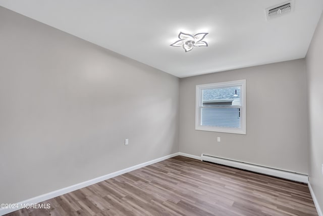 empty room with a baseboard heating unit and light wood-type flooring