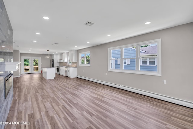 unfurnished living room with a baseboard heating unit, light hardwood / wood-style flooring, and french doors