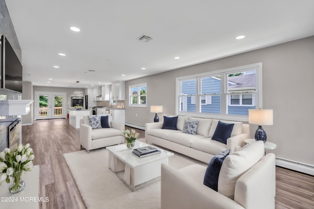 living room with a baseboard heating unit, light hardwood / wood-style floors, and french doors