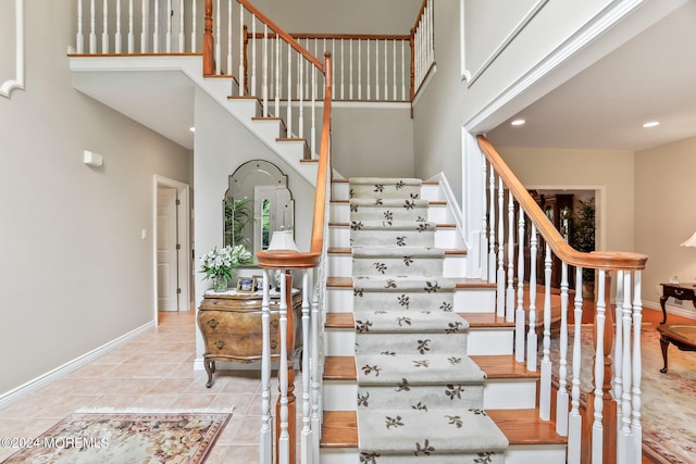 stairs with a high ceiling, recessed lighting, tile patterned floors, and baseboards