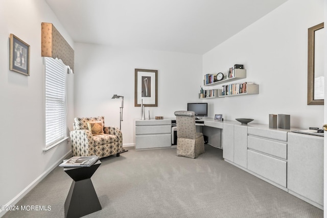 home office with baseboards, built in desk, and light colored carpet