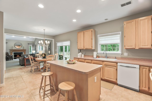 kitchen with visible vents, a center island, white dishwasher, light brown cabinetry, and a sink