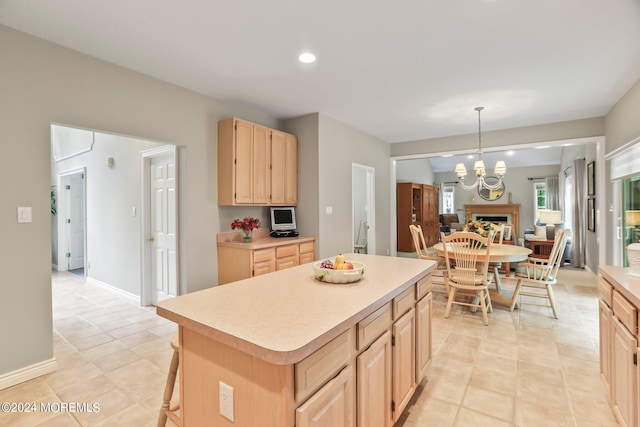 kitchen featuring a chandelier, hanging light fixtures, light countertops, a center island, and light brown cabinetry