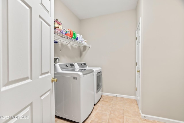 washroom with laundry area, baseboards, washer and clothes dryer, and light tile patterned flooring