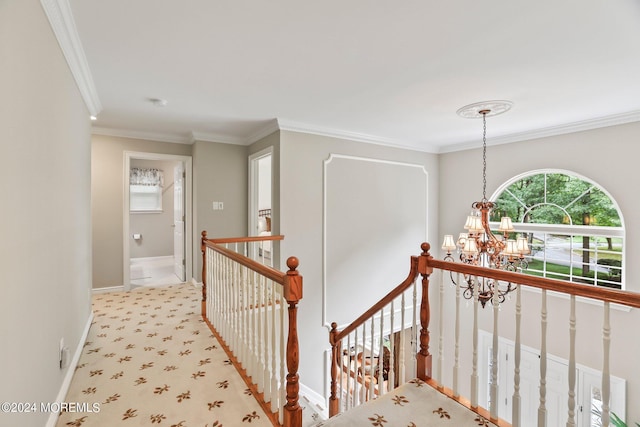 hall with a notable chandelier, light carpet, an upstairs landing, baseboards, and ornamental molding