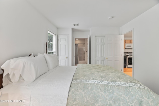 bedroom with visible vents, multiple closets, and ensuite bathroom