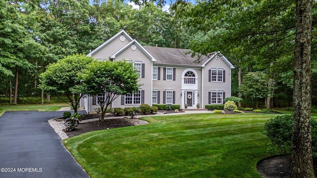 colonial house with aphalt driveway and a front yard