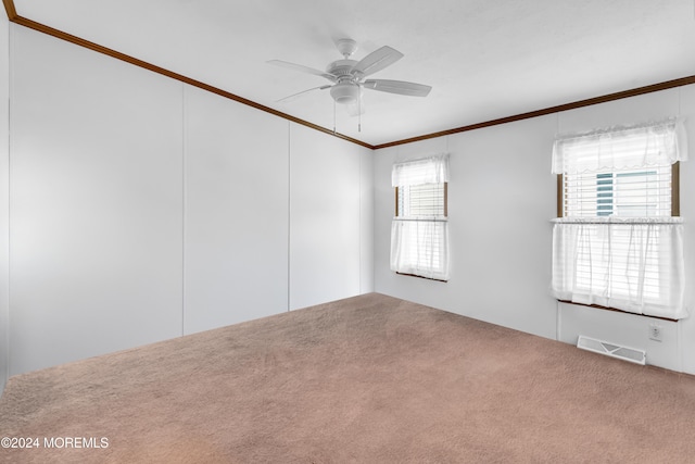 unfurnished room featuring a wealth of natural light, ceiling fan, crown molding, and carpet