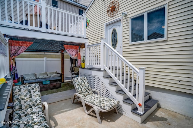 view of exterior entry featuring a patio, fence, and an outdoor living space