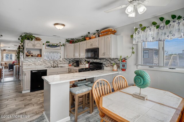 kitchen featuring light countertops, black appliances, a breakfast bar area, and a peninsula