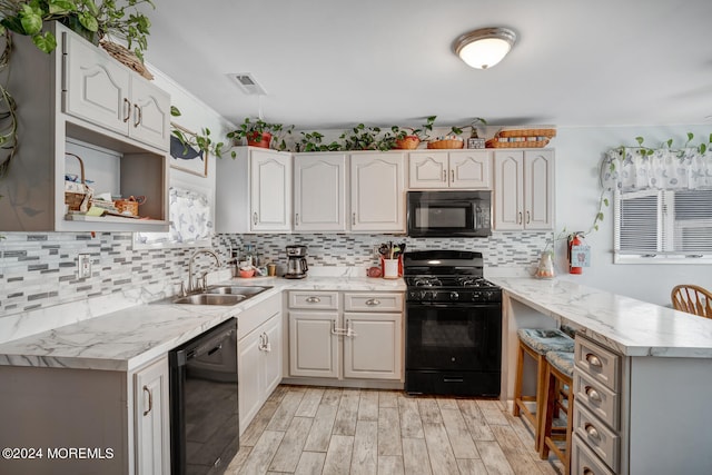 kitchen with visible vents, white cabinetry, a sink, a peninsula, and black appliances