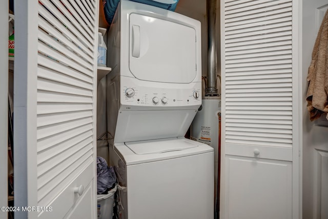 laundry area with stacked washing maching and dryer, water heater, and laundry area