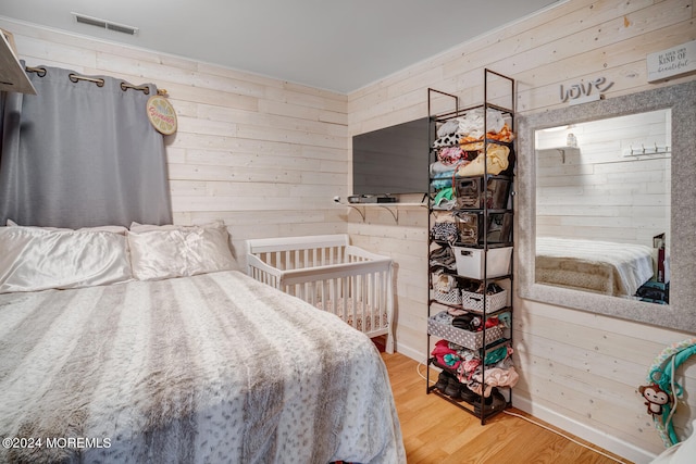 bedroom featuring visible vents, wood walls, and wood finished floors