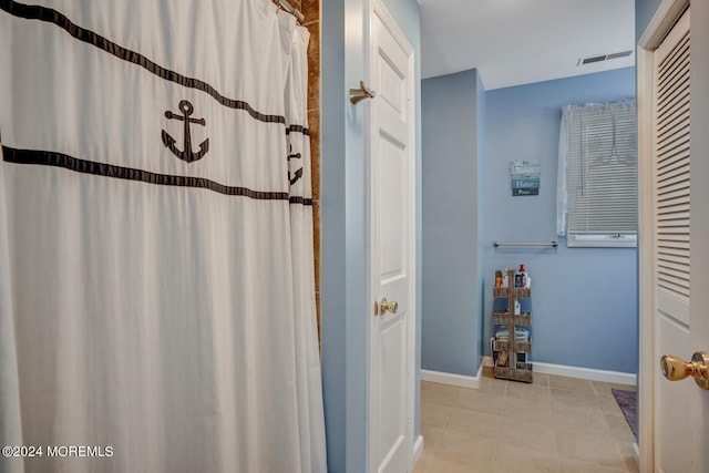 bathroom featuring a shower with shower curtain, tile patterned flooring, visible vents, and baseboards