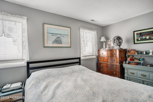 bedroom with a textured ceiling and visible vents