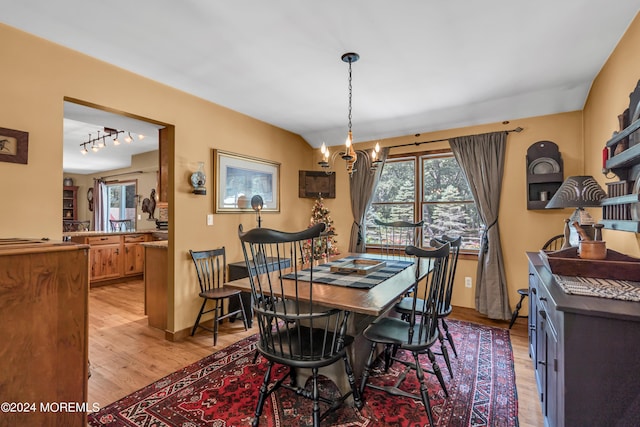 dining room with an inviting chandelier, track lighting, and light hardwood / wood-style floors