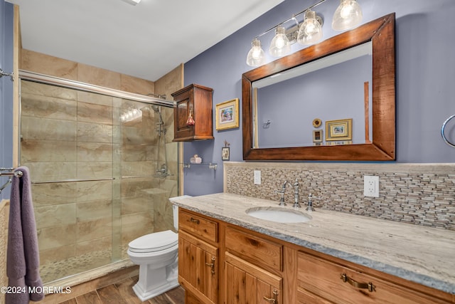 bathroom with hardwood / wood-style flooring, backsplash, vanity, an enclosed shower, and toilet