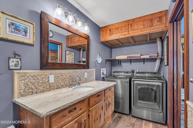 laundry area with sink, washer and dryer, and light wood-type flooring