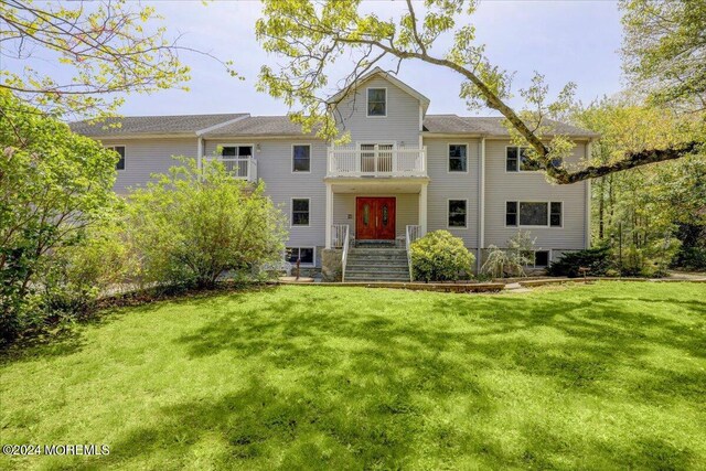 view of front of home featuring a balcony and a front lawn