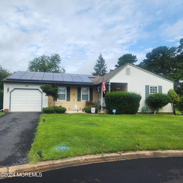 ranch-style house featuring solar panels, a garage, and a front lawn