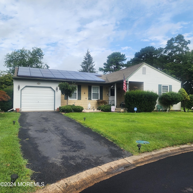 single story home featuring a garage, solar panels, and a front lawn