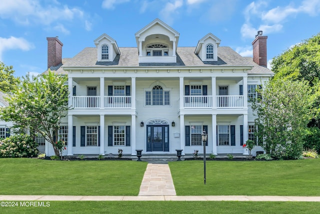 view of front of house with a balcony and a front lawn