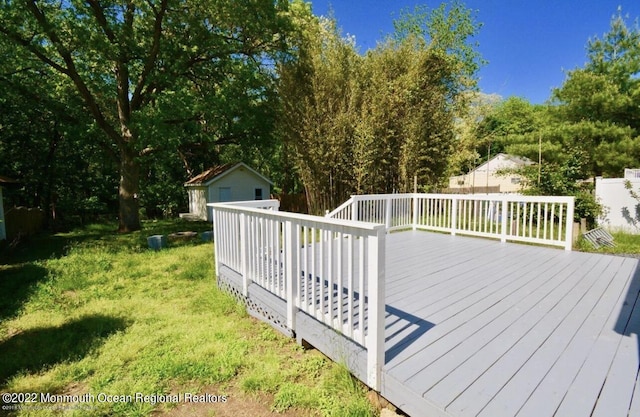 wooden deck featuring a storage unit and a lawn