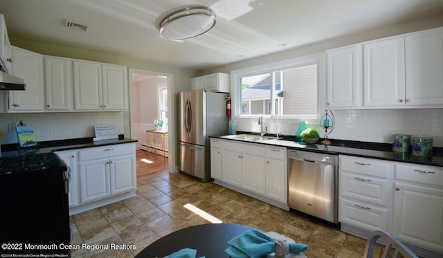 kitchen with appliances with stainless steel finishes, sink, tasteful backsplash, and white cabinets