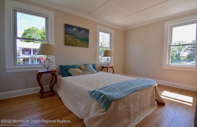 bedroom featuring hardwood / wood-style flooring, crown molding, and multiple windows