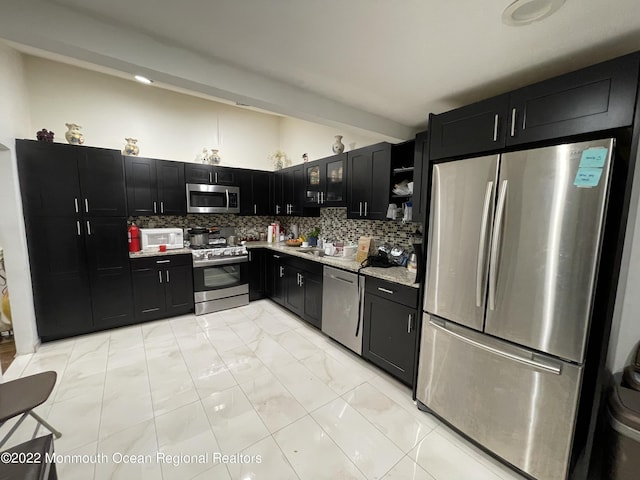 kitchen with appliances with stainless steel finishes, tasteful backsplash, light stone countertops, beamed ceiling, and sink