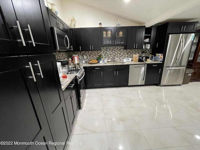 kitchen featuring sink, stainless steel appliances, vaulted ceiling, and backsplash