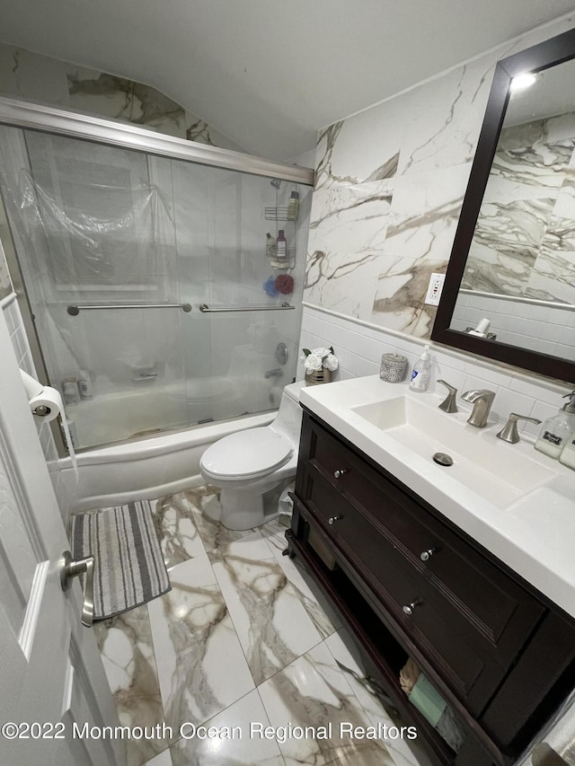 full bathroom featuring toilet, tile walls, bath / shower combo with glass door, and vanity