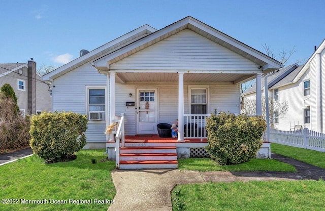 bungalow-style home with a front lawn, a porch, and cooling unit