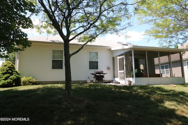 rear view of property featuring a sunroom and a lawn