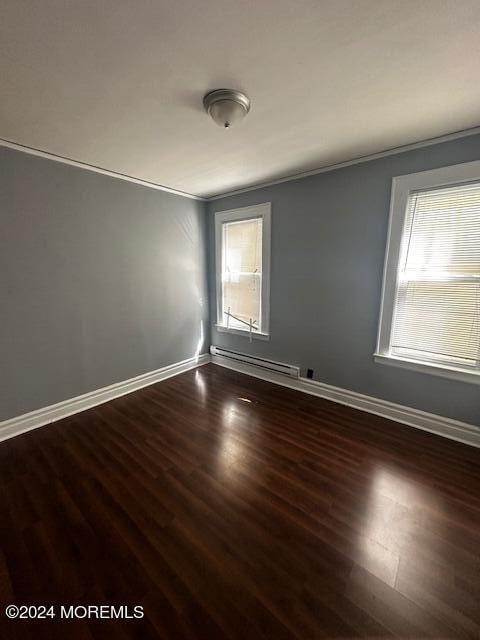 unfurnished room featuring a baseboard radiator, hardwood / wood-style flooring, and crown molding