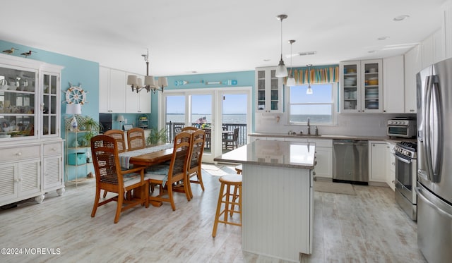 kitchen with a center island, decorative light fixtures, white cabinetry, and appliances with stainless steel finishes