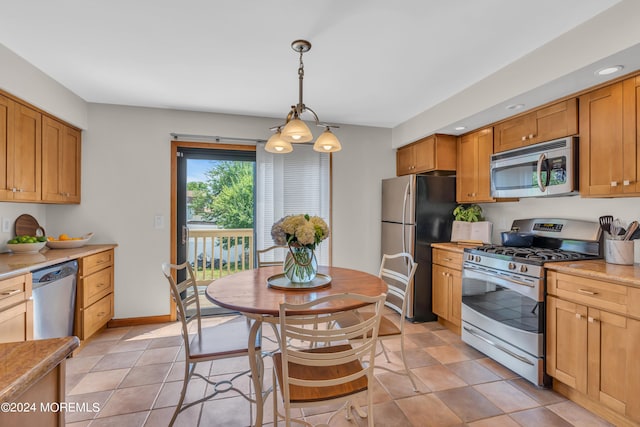 kitchen with stainless steel appliances, light tile patterned floors, and pendant lighting