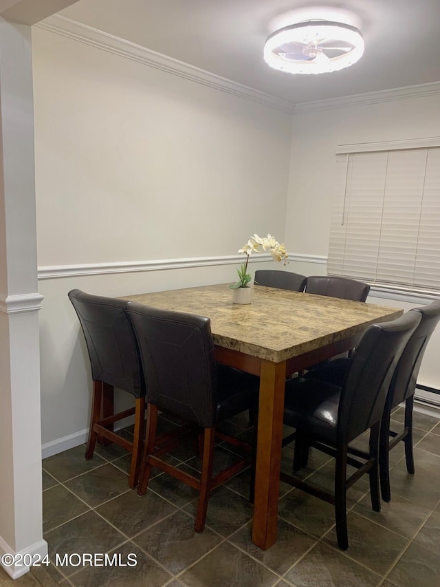 dining room with dark tile patterned flooring and ornamental molding