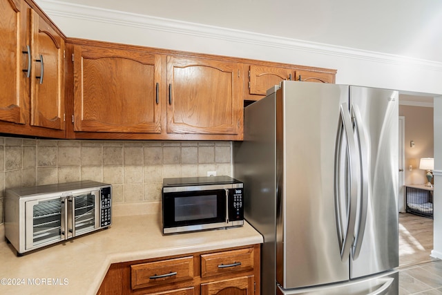 kitchen with crown molding, appliances with stainless steel finishes, and tasteful backsplash