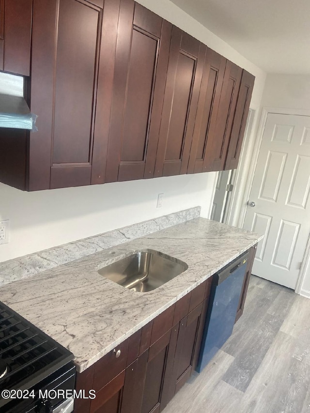 kitchen featuring dishwasher, light stone counters, light wood finished floors, and a sink