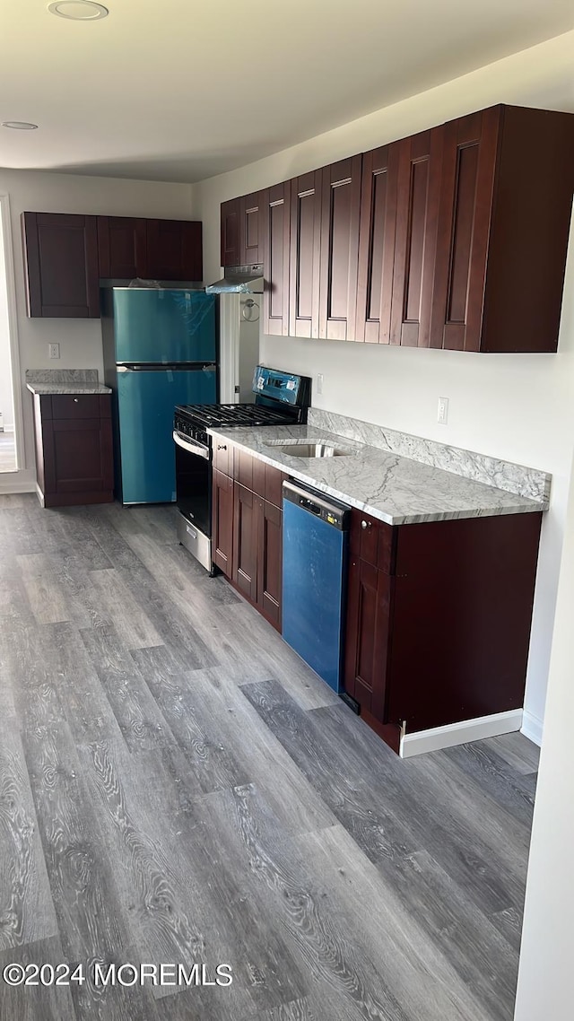 kitchen featuring light wood finished floors, freestanding refrigerator, stainless steel gas range, dishwasher, and under cabinet range hood