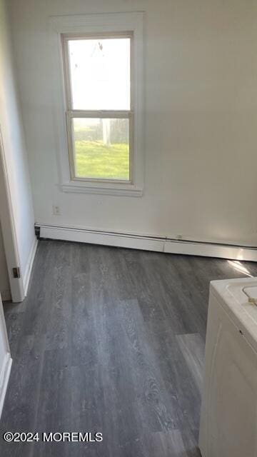 unfurnished room with a baseboard heating unit, washer / clothes dryer, dark wood-style flooring, and baseboards