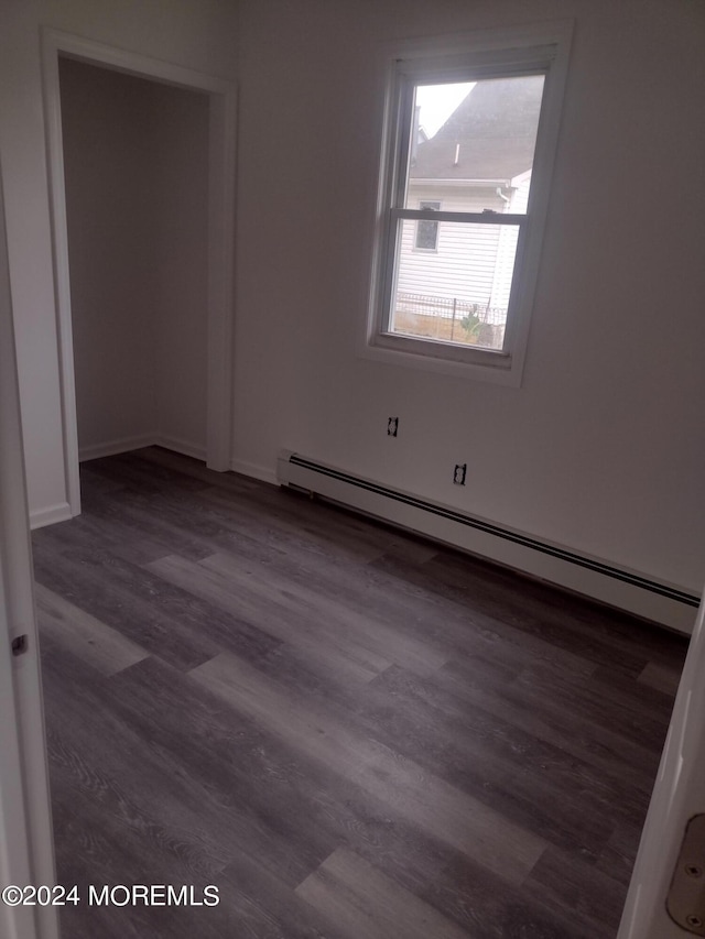 spare room with baseboards, baseboard heating, and wood finished floors