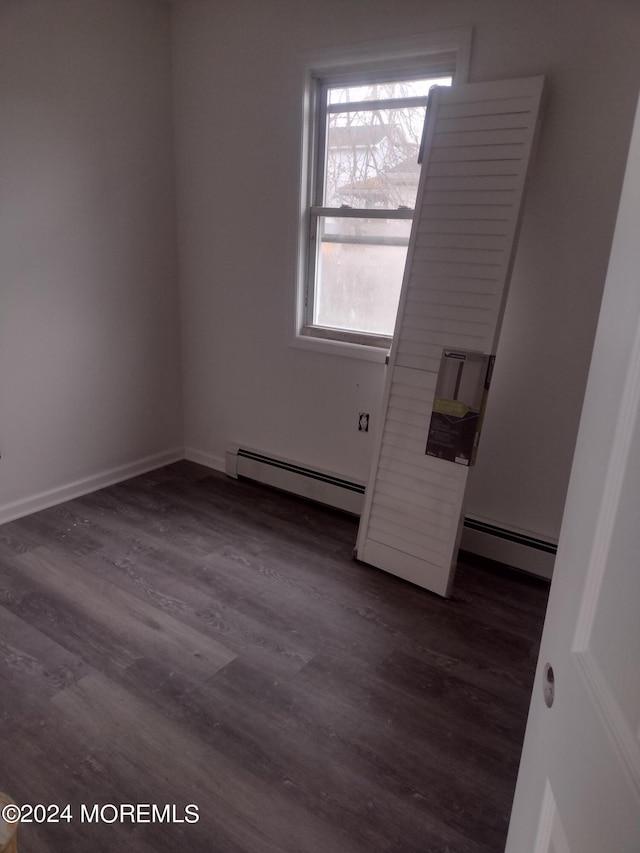 unfurnished room with dark wood-type flooring, a baseboard radiator, and baseboards