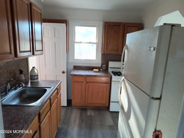 kitchen featuring dark countertops, white appliances, brown cabinets, and a sink