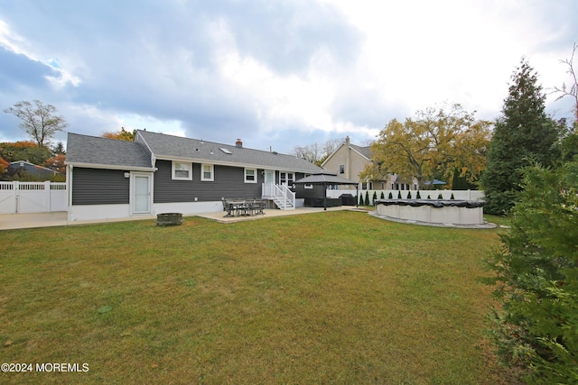 rear view of property featuring a patio area, a covered pool, and a yard