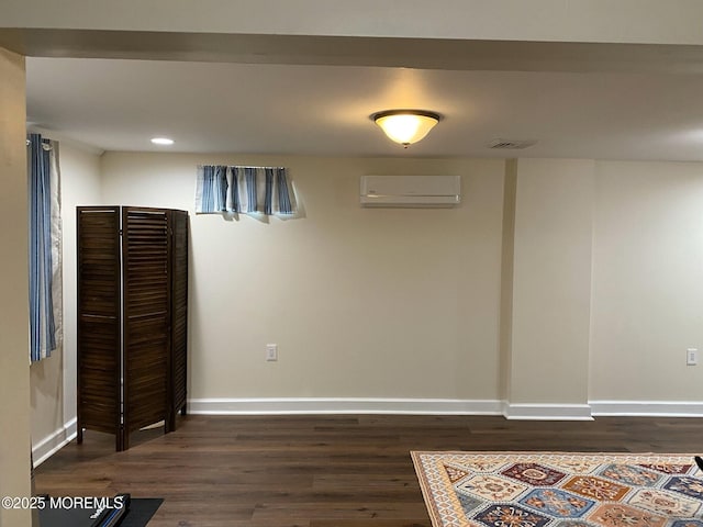 basement featuring dark hardwood / wood-style flooring and a wall mounted AC